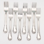 MERIDIONAL EPNS 100. Elegante conjunto de garfos para peixe confeccionado em metal espessurado à prata(EPNS 100), cabo violinado com filetes longitudinais em baixo-relevo e terminação ornamentada por composição de concheados, volutas, flores e folhagens em relevo. Marca da manufatura puncionada no verso. Composto de oito(08) unidades. Medida: Comp.: 16,5 cm.