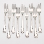 MERIDIONAL EPNS 100. Elegante conjunto de garfos para sobremesa confeccionado em metal espessurado à prata(EPNS 100), cabo violinado com filetes longitudinais em baixo-relevo e terminação ornamentada por composição de concheados, volutas, flores e folhagens em relevo. Marca da manufatura puncionada no verso. Composto de nove(09) unidades. Medida: Comp.: 17 cm.