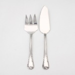 MERIDIONAL EPNS 100. Um(01) garfo e uma(01) espátula para serviço de peixe confeccionados em metal espessurado à prata(EPNS 100), cabo violinado com filetes longitudinais em baixo-relevo e terminação ornamentada por composição de concheados, volutas, flores e folhagens em relevo. Marca da manufatura puncionada no verso. Medida: Garfo: Comp.: 20,5 x Larg.: 5 cm; Espátula: Comp.: 24,5 x Larg.: 4 cm.