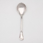 MERIDIONAL EPNS 100. Elegante colher para açúcar confeccionada em metal espessurado à prata(EPNS 100), repuxada com formato de concha, cabo violinado com filetes longitudinais em baixo-relevo e terminação ornamentada por composição de concheados, volutas, flores e folhagens em relevo. Marca da manufatura puncionada no verso. Medida: Comp.: 14,5 cm.