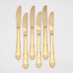 Belíssimo conjunto de facas confeccionadas em metal, dotado de profusa decoração em douradura, fabricação japonesa, manufatura For Ever; cabo de ponta oval, ornamentado por composição rocaille em relevo, constituída por volutas, concheados, flores e folhagens de inspiração Luís XV. Lâmina com dorso serrilhado. Marca da manufatura gravada na lâmina. Composto de seis(06) unidades. Medida: Comp.: 21,5 cm.
