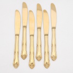 Belíssimo conjunto de facas para sobremesa confeccionadas em metal, dotado de profusa decoração em douradura, fabricação japonesa, manufatura For Ever; cabo de ponta oval, ornamentado por composição rocaille em relevo, constituída por volutas, concheados, flores e folhagens de inspiração Luís XV. Lâmina com dorso serrilhado. Marca da manufatura gravada na lâmina. Composto de seis(06) unidades. Medida: Comp.: 17 cm.