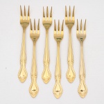 Belíssimo conjunto de garfos para sobremesa / petiscos confeccionado em metal, dotado de profusa decoração em douradura, fabricação japonesa, manufatura For Ever; cabo de ponta oval, ornamentado por composição rocaille em relevo, constituída por volutas, concheados, flores e folhagens de inspiração Luís XV. Marca da manufatura no verso do cabo. Composto de seis(06) unidades. Medida: Comp.: 14 cm.