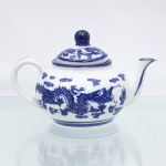 Bule para chá em porcelana chinesa, de bojo globular achatado, com alça arqueada, bico vertedor curvo e tampa de encaixe com pomo esférico. Esmaltação vítrea na cor branca, com decoração em azul sob o vidrado composta por dragões chineses de cinco garras entre nuvens estilizadas e chamas, distribuídos ao redor do bojo; tampa com motivos de dragões e nuvens. Filetes azuis circundam a base, o bordo, a tampa e o bico vertedor. Base com marca Happy Dining-Room / Microwave Oven Safe / Made in China / 1999 (K-44), indicando fabricação chinesa contemporânea, datada de 1999. Medidas: Alt.: 11,5 x Comp.: 17,5 x Larg.: 11cm.