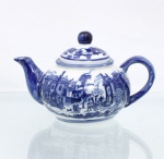 Bule para chá em porcelana chinesa, de bojo globular achatado, com alça arqueada, bico vertedor curvo e tampa de encaixe com pomo esférico. Esmaltação vítrea na cor branca, com decoração em azul sob o vidrado, composta por cena contínua de paisagem com construções de arquitetura europeia, figuras humanas, cavaleiros, árvores, pavilhões e elementos de jardim. Tampa decorada em azul com motivos fitomórficos e paisagísticos. Bico vertedor e alça recobertos por azul, com filetes azuis no bordo e junto à base.  Base com marca Happy Dining-Room / Microwave Oven Safe / Made in China / 1999 (K-44), indicando fabricação chinesa contemporânea, datada de 1999. Medidas: Alt.: 11 x Comp.: 18 x Larg.: 12cm.