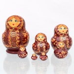 Conjunto de bonecas tradicionais russas do tipo matryoshka, confeccionadas em madeira torneada e pintada à mão. Composto por sete figuras encaixáveis de dimensões decrescentes, o grupo apresenta acabamento em verniz brilhante sobre fundo bordeaux. A ornamentação exibe feições estilizadas e trajes típicos eslavos (sarafan) decorados com purpurina dourada, colares perolados e ramagens espiraladas de inspiração Khokhloma que cobrem as laterais e o verso. Medidas: Alt.: 12 x Diam.: 8cm.Medidas: Alt.: 9 x Diam.: 6,5cm.Medidas: Alt.: 7 x Diam.: 5cm.Medidas: Alt.: 5 x Diam.: 4cm.Medidas: Alt.: 3,5 x Diam.: 2,5cm.Medidas: Alt.: 2,5 x Diam.: 2cm.Medidas: Alt.: 1,5 x Diam.: 1,5cm.
