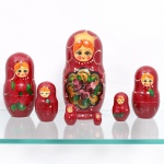 Conjunto de bonecas russas encaixáveis tipo Matrioska, executadas em madeira torneada e pintadas à mão, composto por oito(08) figuras de dimensões graduadas. Corpos com fundo em tonalidade vermelho-bordô, representações femininas com cabelos em tom alaranjado, olhos azuis e faces policromadas. Decoração fitomórfica com flores e folhagens em tons de vermelho, rosa, verde, preto e dourado, complementada por elementos circulares e pontilhados. Peças constituídas por duas partes encaixáveis, à exceção da figura de menor dimensão, maciça. Medidas: Alt.: 21 x Diam.: 9cm.Medidas: Alt.: 15,5 x Diam.: 7cm.Medidas: Alt.: 12,5 x Diam.: 6cm.Medidas: Alt.: 9 x Diam.: 4,5cm.Medidas: Alt.: 6,5 x Diam.: 3,5cm.Medidas: Alt.: 4,5 x Diam.: 2,5cm.Medidas: Alt.: 3 x Diam.: 1,5cm.