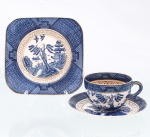 Trio para chá em faiança japonesa, Imperial Ironstone Ware, N.K.T., Japão, meados do século XX. Composto por xícara, pires e prato de sobremesa quadrangular com cantos arredondados. Decoração derivada do Willow Pattern, em azul sob esmalte, com paisagem orientalista constituída por arquitetura, ponte, arvoredo, curso d'água, embarcação e aves em voo; cercaduras geométricas em azul e sépia e filetação dourada. Superfície com craquelê de esmalte. No reverso, marca "Imperial Ironstone Ware - N.K.T. - Made in Japan", vinculada à produção da Nihon Koshitsu Toki, atual NIKKO, manufatura fundada em Kanazawa em 1908. Medidas xícara: Alt.: 5,5 x Comp.: 10 x Larg.: 8cm.Medidas pires: Diam.: 13,5cm.Medidas prato: Comp.: 14 x Larg.: 14cm.