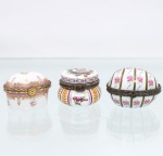 Três(03) caixas porta-joias em porcelana, coleção Porcelain Art. Caixas de pequenas dimensões, destinadas à guarda de joias e objetos pessoais, com corpos de formatos distintos, tampas articuladas, montagens metálicas ornamentadas e fechos frontais. Decoração policromada composta por motivos florais, ramagens, reservas e faixas geométricas, com emprego de rosa, púrpura, verde, ocre e dourado. A peça central apresenta corpo abaulado com painéis verticais de folhagens e flores; a lateral direita, formato ovalado com gomos verticais alternando rosas e filetes; a lateral esquerda, corpo de contorno retangular arredondado com frisos de ramagens douradas sobre faixa rosa. Conservam marca estampada "Porcelain Art  PA" na base. Medidas: Alt.: 3,5 x Comp.: 5,5 x Larg.: 4,5cm.Medidas: Alt.: 3,5 x Comp.: 5 x Larg.: 4cm.Medidas: Alt.: 3 x Diam.: 4cm.