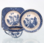 Trio para chá em faiança japonesa, Imperial Ironstone Ware, N.K.T., Japão, meados do século XX. Composto por xícara, pires e prato de sobremesa quadrangular com cantos arredondados. Decoração derivada do Willow Pattern, em azul sob esmalte, com paisagem orientalista constituída por arquitetura, ponte, arvoredo, curso d'água, embarcação e aves em voo; cercaduras geométricas em azul e sépia e filetação dourada. Superfície com craquelê de esmalte. No reverso, marca "Imperial Ironstone Ware - N.K.T. - Made in Japan", vinculada à produção da Nihon Koshitsu Toki, atual NIKKO, manufatura fundada em Kanazawa em 1908. Medidas xícara: Alt.: 5,5 x Comp.: 10 x Larg.: 8cm.Medidas pires: Diam.: 13,5cm.Medidas prato: Comp.: 14 x Larg.: 14cm.