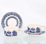 Duas(02) xícaras para chá em faiança nacional, manufatura Oxford. Esmaltação de tom marfim, dotada de decoração monocromática azul aplicada por transferência, segundo o padrão" Blue Willow", de inspiração oriental, representando pagodes, pontes, embarcações, árvores, cercados e elementos florais. Pires com aba ornamentada por reservas geométricas, reticulados, motivos fitomórficos e frisos de caráter orientalista. Marca de fábrica sob a base: "Oxford  Made in Brazil". Medidas: Xícara: Alt.: 6 x Comp.: 11,5 x Larg.: 9cm; Pires: Diam.: 15 cm.