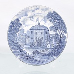 Prato decorativo em faiança de pasta dura, profuzido pela manufatura Ridgway em Staffordshire, Inglaterra, pertencente à série "Shakespeares Country", introduzida durante a segunda metade do século XX. Esmaltagem vítrea na cor branca com aba sutilmente recortada em gomos ondulares e debrum liso; superfície integralmente recoberta por ornamentação de transferência sob o vidrado em tom azul-cobalto, contendo céu anuviado e copas de árvores que se estendem pelas bordas. Centro abriga composição pictórica que reproduz uma gravação manual, retratando o edifício histórico "The Globe Theatre in the year 1599" com figuras humanas em trajes de época diante do portal, ladeado por vegetação e árvores delinfadas em hachuras. Verso exibe base com carimbo de manufatura transferido na cor azul, envolto por guirlanda floral com as inscrições "Genuine Hand Engravings EST. by Ridgway of 1792 Staffordshire England / ALL COLORS GUARANTEED UNDERGLAZE 78 AND DETERGENT PROOF / Shakespeares Country". O reverso apresenta ainda etiqueta comercial da importadora "Drohaoser Com. Ind. Ltda." com a indicação de nacionalização na Zona Franca de Manaus.  Medida: Diam.: 20 cm.