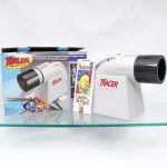 Projetor para ampliação e reprodução de imagens, desenhos, padrões e outros originais opacos, modelo Tracer 225-360, confeccionado em material sintético, com objetiva regulável e sistema interno de iluminação e reflexão. Etiqueta do fabricante Artograph, Minneapolis, Minnesota, USA, especificando alimentação de 120 V, 50/60 Hz e potência de 100 W. Acompanha embalagem original e material impresso. Equipamento destinado à projeção de imagens sobre superfícies para ampliação, desenho e transferência de contornos.Medidas caixa: Alt.: 24 x Comp.: 35 x Larg.: 15cm; Medidas projetor: Alt.: 23,5 x Comp.: 32 x Larg.: 14,5cm