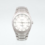 Relógio de pulso masculino Orient, Japão, circa 2000. Caixa e bracelete articulado em aço inoxidável, mostrador branco com índices horários aplicados, escala periférica de minutos e ponteiros centrais para horas, minutos e segundos. Movimento japonês a quartzo. Mostrador com inscrições "Orient", "Water Resist 100m" e "Japan Movt". Fundo gravado "MBSS1077  All Stainless Steel  Water Resist 100m  PPM-195". Fecho desdobrável com assinatura Orient. Apresenta sinais de uso e riscos superficiais. Não está funcionando. Medida da caixa: Diam.: 40mm.