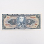 Numismática / Cédulas do Brasil. Cédula de 2 Cruzeiros, República dos Estados Unidos do Brasil, Série 583A, número 053733. Anverso com impressão predominante em tonalidade azul-acinzentada, com efígie do Duque de Caxias em medalhão central, ladeada por rosáceas com o valor facial 2; inscrições Tesouro Nacional, República dos Estados Unidos do Brasil e Dois Cruzeiros  Valor Recebido. Reverso com impressão predominante em tonalidade laranja, apresentando vista aérea da Escola Militar de Resende, atual Academia Militar das Agulhas Negras, ladeada por elementos ornamentais e algarismos indicativos do valor facial. Impressão pela American Bank Note Company. Brasil, década de 1950.
