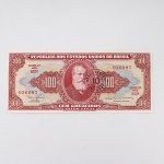 Numismática / Cédulas do Brasil. Cédula de 100 Cruzeiros, República dos Estados Unidos do Brasil, 2ª Estampa, Série 852A, número 026087. Anverso em tonalidades vermelha, vermelho-rosada, bege e verde-azulada, com efígie de D. Pedro II em medalhão central, ladeada por rosáceas com o valor facial 100; inscrições Tesouro Nacional, República dos Estados Unidos do Brasil e Cem Cruzeiros  Valor Legal. Apresenta carimbo circular de revalidação monetária do Banco Central, com a inscrição BANCO CENTRAL  10 CENTAVOS, aplicada em 1967 para conversão do valor original de 100 Cruzeiros em 10 centavos de Cruzeiro Novo. Reverso em tonalidade vermelho-rosada, com composição alegórica da Cultura Nacional, representada por figura feminina sentada junto a globo, livros e instrumentos, tendo paisagem ao fundo. Impressão pela Thomas De La Rue & Company Limited, Londres. Brasil, circa 1953-1959; revalidada em 1967.