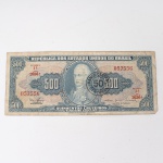 Numismática / Cédulas do Brasil. Cédula de 500 Cruzeiros (Cr$ 500,00), pertencente ao padrão monetário brasileiro do Cruzeiro, emissão do Tesouro Nacional. Estampa 1A, Série 2036A, número de ordem 057556, impressa pela American Bank Note Company, Nova York. Anverso com efígie de D. João VI em medalhão central, ladeada pelo valor facial 500 e inscrições institucionais, apresentando carimbo circular do Banco Central com conversão para 50 centavos, aplicado para circulação no padrão Cruzeiro Novo, introduzido em 1967. Reverso com alegoria intitulada "Abertura dos Portos", composta por figura feminina e embarcações ao fundo, ladeada por cartuchos com o valor facial. Impressão sobre papel fiduciário. Brasil, 1967. A conversão de cédulas do Cruzeiro por meio de carimbos com os novos valores integrou oficialmente a implantação do Cruzeiro Novo.