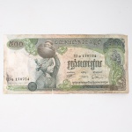 Numismática / Cédulas Estrangeiras. Cédula de 500 Riels do Camboja, emitida pelo Banque Nationale du Cambodge, número 170754, integrada à última reforma monetária da República Khmer anterior à derrocada do regime em 1975. Anverso com figura feminina transportando recipiente sobre a cabeça, acompanhada de ornamentação inspirada na arte Khmer e inscrições em alfabeto khmer. Reverso com composição dedicada à agricultura, representando trabalhadores em campos de arroz, máquinas agrícolas e paisagem rural, complementada por friso com figuras em relevo de inspiração Khmer e valor facial 500. Impressão policromática sobre papel fiduciário. Camboja, emissão de 19721975.