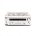 Receiver de áudio e vídeo Sony STR-DE895, Japão, 2003. Receiver multicanal para sistema de home theater, modelo STR-DE895, com sintonizador FM/AM e amplificação de seis canais. Compatível com Dolby Digital, Dolby Digital EX, Dolby Pro Logic II, DTS, DTS-ES e DTS Neo:6, além do sistema Sony Digital Cinema Sound. Potência nominal em estéreo de 100 W + 100 W em 8 ohms, de 20 Hz a 20 kHz, com distorção harmônica total de 0,09%; configuração multicanal com saídas para caixas frontais, central, surround e surround back. Painel frontal com display digital, comandos de volume, seleção de entrada, sintonia e modos de decodificação, saída para fones e entradas auxiliares de áudio, vídeo e digital óptica. Painel posterior provido de conexões analógicas e digitais, incluindo Phono, CD/SACD, MD/Tape, DVD, TV/SAT, vídeo composto, S-Video, vídeo componente, entradas ópticas e coaxial, entrada multicanal 5.1/6.1 e terminais para caixas acústicas. Acabamento prateado, apresentando marcas de uso, sujidades, pontos de oxidação e perdas superficiais no gabinete, conforme registro fotográfico. Funcionamento não verificado, sem garantias de funcionamento. Medidas: Alt.: 16 x Comp.: 43 x Larg.: 32,5cm.