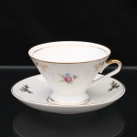 Porcellana Mauá, Mauá - SP(Fundada em 1937 por Fritz Erwin Schmidt / ativa até 1968). Chávena para chá em porcelana nacional, circa 1950-60. Esmaltagem vítrea na cor branca, decoração em estampagem policromada, composta por pequenos ramos florais, com motivos florais estilizados em estampagem policromada e douradura aplicada, filetagem dourada contornando a boca, base e borda do pires. Bojo obcônico assentado sobre base circular, alça lateral estilizada. Marca da manufatura no verso. Medidas: Xícara: Alt.: 6 x Comp.: 11 x Larg.: 9,5 cm; Pires: Diam.: 13,5 cm.
