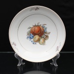 Porcelana Schmidt, Santa Catarina, Brasil (Fundada em 1945). Pequeno bowl em porcelana nacional, esmaltagem vítre na cor branca, formato hemisférico raso, aba lisa e filetes dourados delimitando a borda e o cavado. Ao centro, composição em estampagem policromada de frutos e folhagens, destacando abóbora, cachos de uvas e frutos ovais; aba ornada por pequenos ramos florais espaçados. Marca da manufatura no verso. Medidas: Alt.: 6 x Diam.: 25 cm.