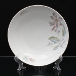 Porcelana, Steatita e Magnésia S/A, Campo Largo - PR(Fundada em 1954). Bowl em porcelana naiconal, esmaltagem vítrea na cor branca, formato hemisférico, decoração floral assimétrica composta por lírios estilizados em tons de rosa, cinza, azul e verde, distribuídos pela aba, com pequenos ramos complementares. Marca da manufatura no verso. Medidas: Alt.: 6,5 x Diam.: 23,5 cm.