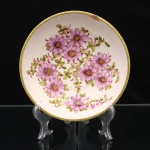 Tigela circular em cerâmica portuguesa esmaltada, formato hemisférico raso, bordo realçado por filete verde. Decoração policroma executada à mão, com composição floral em tons de rosa e violeta. Exterior ornamentado por friso vegetal estilizado em verde. No reverso, inscrição manuscrita em vermelho: A. Nova e. 412 L, Cerâmica Artística A Nova, Alcobaça - Portugal. Medidas: Alt.: 6 x Diam.: 19,5 cm.