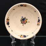 Bowl executado em faiança, face exterior revestido em azul e interior em tonalidade marfim. Decoração floral policroma pintada à mão, constituída por pequenos buquês distribuídos no centro e junto à aba, em azul-cobalto, rosa, amarelo, verde e negro, interligados por filetes lineares. Superfície interna com craquelê de esmalte e sinais de uso. Bordo com perdas de esmalte e lascamento localizado, conforme fotografias. Medidas: Alt.: 7 x Diam.: 24cm.