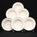 W.H. GRINDLEY, Staffordshire - Inglaterra(Fundada por William Harry Grindley em 1880). Conjunto de pratos fundo em faiança inglesa, padrão "CREAMPETAL", c.1940-50. Esmaltagem vítre de tonalidade marfim claro, orla modelada com faixa perimetral ondulada, percorrida por perolados relevados na própria pasta, ornamentada por filetagem à ouro contornando a borda e a caldeira. Apresenta ínfimos degastes na douradura. Marca da manufatura no verso. Composto de seis(06) unidades. Medida: Diam.: 23 cm.