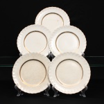 W.H. GRINDLEY, Staffordshire - Inglaterra(Fundada por William Harry Grindley em 1880). Conjunto de pratos rasos em faiança inglesa, padrão "CREAMPETAL", c.1940-50. Esmaltagem vítre de tonalidade marfim claro, orla modelada com faixa perimetral ondulada, percorrida por perolados relevados na própria pasta, ornamentada por filetagem à ouro contornando a borda e a caldeira. Apresenta ínfimos degastes de uso na douradura, e manchas do tempo(um acantuado). Marca da manufatura no verso. Composto de cinco(05) unidades. Medida: Diam.: 23 cm.