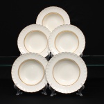 W.H. GRINDLEY, Staffordshire - Inglaterra(Fundada por William Harry Grindley em 1880). Conjunto de pratos fundo em faiança inglesa, padrão "CREAMPETAL", c.1940-50. Esmaltagem vítre de tonalidade marfim claro, orla modelada com faixa perimetral ondulada, percorrida por perolados relevados na própria pasta, ornamentada por filetagem à ouro contornando a borda e a caldeira. Apresenta ínfimos degastes na douradura. Marca da manufatura no verso. Composto de cinco(05) unidades. Medida: Diam.: 23 cm.