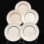 W.H. GRINDLEY, Staffordshire - Inglaterra(Fundada por William Harry Grindley em 1880). Conjunto de pratos rasos em faiança inglesa, padrão "CREAMPETAL", c.1940-50. Esmaltagem vítre de tonalidade marfim claro, orla modelada com faixa perimetral ondulada, percorrida por perolados relevados na própria pasta, ornamentada por filetagem à ouro contornando a borda e a caldeira. Apresenta ínfimos degastes de uso na douradura, e manchas do tempo(um acantuado). Marca da manufatura no verso. Composto de cinco(05) unidades. Medida: Diam.: 23 cm.