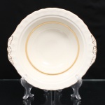 W.H. GRINDLEY, Staffordshire - Inglaterra(Fundada por William Harry Grindley em 1880). Saladeira em faiança inglesa, padrão "CREAMPETAL", c.1940-50. Esmaltagem vítrea de tonalidade marfim claro, formato hemisférico, orla modelada com faixa perimetral ondulada, percorrida por perolados relevados na própria pasta, ornamentada por filetagem à ouro contornando a borda e a caldeira, abas laterais integradas e decoradas com ramagens. Marca da manufatura no verso. Medidas: Alt.: 7 x Diam.: 24 cm.