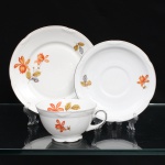 Porzellanfabrik Zeh, Scherzer & Co, Baviera - Alemanha (Fundada em 1880). Excepcional trio para chá em porcelana alemã da década de 1930, estilo e período Art Déco. Composto de chávena para chá, prato para sobremesa e pires. Esmaltagem vítrea na cor branca, dotada de decoração em estampagem policromada, com flores e ramagens outonais nas tonalidades coral, ocre, azul e amarelo, realçada por filetação prateada nas bordas e detalhes. Bojo hemisférico assentado sobre base cirular elevada de borda recortada, asa lateral em voluta. Bordas da xícara, pires e prato possuem contorno relevado com sucessão de frisos radias interrompidos por folha de acanto estilizada. Marca da manufatura ao fundo, acompanhada de selo comemorativo de 50 anos de fundação da marca com a inscrição "50 JAHRE"(O timbre "50 Jahre" (50 anos) identifica a tiragem limitada produzida pela Porzellanfabrik Zeh, Scherzer & Co. AG de forma exclusiva no decorrer do ano de 1930, em celebração ao cinquentenário de fundação da fábrica em Rehau, na Baviera). Medidas: Xícara: Alt.: 5,5 x Comp.: 12 x Larg.: 10 cm. Prato: Diam.: 17 cm; Pires: Diam.: 15 cm.