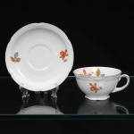 Porzellanfabrik Zeh, Scherzer & Co, Baviera - Alemanha (Fundada em 1880). Excepcional chávena para chá em porcelana alemã da década de 1930, estilo e período Art Déco. Esmaltagem vítrea na cor branca, dotada de decoração em estampagem policromada, com flores e ramagens outonais nas tonalidades coral, ocre, azul e amarelo, realçada por filetação prateada nas bordas e detalhes. Bojo hemisférico assentado sobre base cirular elevada de borda recortada, asa lateral em voluta. Bordas da xícara e do pires possuem contorno relevado com sucessão de frisos radias interrompidos por folha de acanto estilizada. Marca da manufatura ao fundo, acompanhada de selo comemorativo de 50 anos de fundação da marca com a inscrição "50 JAHRE"(O timbre "50 Jahre" (50 anos) identifica a tiragem limitada produzida pela Porzellanfabrik Zeh, Scherzer & Co. AG de forma exclusiva no decorrer do ano de 1930, em celebração ao cinquentenário de fundação da fábrica em Rehau, na Baviera). Medidas: Xícara: Alt.: 5,5 x Comp.: 12 x Larg.: 10 cm; Pires: Diam.: 15 cm.