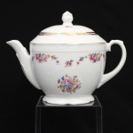 CHODZIEZ PORCELAIN, Chodziez - Polônia(Fundada em 1852 ou 1854, por Hermann Müller e Ludwik Schnorr). Grande bule para chá em porcelana polonesa da década de 1940; esmaltagem vítrea na cor branca, Corpo bojudo de formato hemisférico assentado sobre base circular recortada, alça lateral em voluta, bico vertedor recurvado, tampa abaulada encimada por pomo com feitio de fruto; decorada com padrão floral em estampagem policromada, composto de arranjo floral nas tonalidades rosa, azul, amarelo e verde, e buquês distribuídos no terço superior do bojo sob barrado contínuo relevado na própria pasta. Apresenta filetagem à ouro nas bordas e detalhes. Orla delimitada por barrado contínuo relevado na própria pasta. Marca da manufatura no verso. Medidas: Alt.: 19 x Comp.: 25,5 x Larg.: 16 cm.