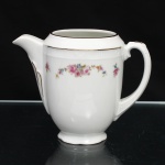 CHODZIEZ PORCELAIN, Chodziez - Polônia(Fundada em 1852 ou 1854, por Hermann Müller e Ludwik Schnorr). Leiteira em porcelana polonesa da década de 1940; esmaltagem vítrea na cor branca, bojo oval alongado assentado sobre base circular recortada, alça lateral em voluta estilizada, bico vertedor curto e recurvado; decorada com padrão floral em estampagem policromada, composto de arranjo floral nas tonalidades rosa, azul, amarelo e verde, e buquês distribuídos no terço superior do bojo sob barrado contínuo relevado na própria pasta. Apresenta filetagem à ouro nas bordas e detalhes. Medidas: Alt.: 11,5 x Comp.: 15 x Larg.: 9 cm.