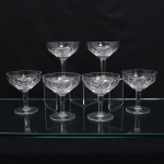 Conjunto de taças para champanhe em meio cristal, diáfano e incolor, de bojo hemisférico talhado com faixa geométrica composta por losangos facetados e cortes diagonais entrecruzados, fuste tubular apoiado sobre base circular. Composto de seis(06) unidades. Medidas. Altura  x Diâmetro:  cm.