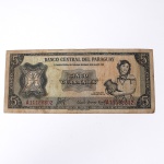Numismática / Cédulas Estrangeiras. Cédula de 5 Guaranies da República do Paraguai, emissão autorizada pelo Decreto-Lei nº 18 de 25 de março de 1952, impressa pela companhia britânica Thomas De La Rue & Company, Limited. O anverso apresenta composição calcográfica em tom marrom predominante sobre fundo geométrico de segurança, ostentando à esquerda o selo oficial da instituição bancária com a inscrição "República del Paraguay - Paz y Justicia" e, à direita, a efígie alegórica "La Mujer Paraguaya"(A Mulher Paraguaia) portando um cântaro. O bilhete porta a numeração de série A11186302. O reverso exibe painel central com a representação arquitetônica do edifício do Hotel Guaraní em Assunção, ladeado por duas grandes rosáceas contendo o numeral de valor de face. O exemplar denota marcas de circulação, descoloração natural e dobras no papel.