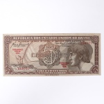 Numismática / Cédulas do Brasil. Cédula de 5 Cruzeiros, Estampa 3, Série 054, emitida pela República dos Estados Unidos do Brasil e impressa pela Casa da Moeda do Brasil no contexto da implantação do padrão monetário Cruzeiro, instituído em 1942 após a reforma que substituiu o sistema do réis. Anverso apresenta composição dominada por busto feminino alegórico representando a República, voltado à esquerda e inscrito em medalhão oval, tendo ao fundo vinheta marítima com embarcação à vela singrando mar agitado, elemento simbólico associado ao progresso econômico, à navegação e ao comércio. No campo central destaca-se elaborada cartela ornamental com o numeral 5 e a legenda CRUZEIROS, envolta por complexa trama de guilhochê de segurança característica da gravura calcográfica. Consta ainda a inscrição legal No Tesouro Nacional se pagará ao portador desta quantia de cinco cruzeiros, acompanhada das assinaturas fac-similares das autoridades monetárias e da indicação tipográfica Estampa 3 Série 054 impressa em vermelho. O reverso exibe vinheta naturalista representando vitória-régia (Victoria amazonica) em paisagem lacustre amazônica, com grandes folhas circulares flutuantes e flor central, enquadrada por moldura ornamental geométrica com os numerais 5 nos cantos e a legenda Estados Unidos do Brasil. Impressão calcográfica com fundos guilhochados de segurança e gravação em aço, padrão característico da produção da Casa da Moeda brasileira nas décadas de 1940-1950. Exemplar em estado aproximado MBC (Muito Bem Conservado), apresentando vincos de circulação, porém com papel íntegro e boa definição da gravura.