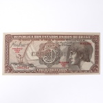 Numismática / Cédulas do Brasil. Cédula de 5 Cruzeiros, Estampa 3, Série 072, emitida pela República dos Estados Unidos do Brasil e impressa pela Casa da Moeda do Brasil no contexto da implantação do padrão monetário Cruzeiro, instituído em 1942 após a reforma que substituiu o sistema do réis. Anverso apresenta composição dominada por busto feminino alegórico representando a República, voltado à esquerda e inscrito em medalhão oval, tendo ao fundo vinheta marítima com embarcação à vela singrando mar agitado, elemento simbólico associado ao progresso econômico, à navegação e ao comércio. No campo central destaca-se elaborada cartela ornamental com o numeral 5 e a legenda CRUZEIROS, envolta por complexa trama de guilhochê de segurança característica da gravura calcográfica. Consta ainda a inscrição legal No Tesouro Nacional se pagará ao portador desta quantia de cinco cruzeiros, acompanhada das assinaturas fac-similares das autoridades monetárias e da indicação tipográfica Estampa 3 Série 072 impressa em vermelho. O reverso exibe vinheta naturalista representando vitória-régia (Victoria amazonica) em paisagem lacustre amazônica, com grandes folhas circulares flutuantes e flor central, enquadrada por moldura ornamental geométrica com os numerais 5 nos cantos e a legenda Estados Unidos do Brasil. Impressão calcográfica com fundos guilhochados de segurança e gravação em aço, padrão característico da produção da Casa da Moeda brasileira nas décadas de 1940-1950. Exemplar em estado aproximado MBC (Muito Bem Conservado), apresentando vincos de circulação, porém com papel íntegro e boa definição da gravura.