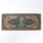 Numismática / Cédulas do Brasil. Cédula de 500 Cruzeiros, República dos Estados Unidos do Brasil, estampa 1ª, série 1301, impressa pela companhia americana American Bank Note Company, circa década de 1950. Anverso apresenta fundo em tons de azul, ostentando medalhão circular central com o retrato de Dom João VI. O papel-moeda porta a numeração 071147. Reverso exibe composição monocromática com gravura calcográfica reproduzindo a composição alegórica "Abertura dos Portos". O exemplar denota marcas evidentes de circulação, sujidade difusa, dobras e desgaste perimetral com pequenas imperfeições nas bordas.