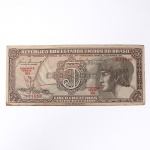 Numismática / Cédulas do Brasil. Cédula de 5 Cruzeiros, Estampa 3, Série 034, emitida pela República dos Estados Unidos do Brasil e impressa pela Casa da Moeda do Brasil no contexto da implantação do padrão monetário Cruzeiro, instituído em 1942 após a reforma que substituiu o sistema do réis. Anverso apresenta composição dominada por busto feminino alegórico representando a República, voltado à esquerda e inscrito em medalhão oval, tendo ao fundo vinheta marítima com embarcação à vela singrando mar agitado, elemento simbólico associado ao progresso econômico, à navegação e ao comércio. No campo central destaca-se elaborada cartela ornamental com o numeral 5 e a legenda CRUZEIROS, envolta por complexa trama de guilhochê de segurança característica da gravura calcográfica. Consta ainda a inscrição legal No Tesouro Nacional se pagará ao portador desta quantia de cinco cruzeiros, acompanhada das assinaturas fac-similares das autoridades monetárias e da indicação tipográfica Estampa 3 Série 034 impressa em vermelho. O reverso exibe vinheta naturalista representando vitória-régia (Victoria amazonica) em paisagem lacustre amazônica, com grandes folhas circulares flutuantes e flor central, enquadrada por moldura ornamental geométrica com os numerais 5 nos cantos e a legenda Estados Unidos do Brasil. Impressão calcográfica com fundos guilhochados de segurança e gravação em aço, padrão característico da produção da Casa da Moeda brasileira nas décadas de 1940-1950. Exemplar em estado aproximado MBC (Muito Bem Conservado), apresentando vincos de circulação, porém com papel íntegro e boa definição da gravura.