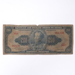 Numismática / Cédulas do Brasil. Cédula de 200 cruzeiros, República dos Estados Unidos do Brasil, 1955. Emissão do Tesouro Nacional, primeira estampa, sem data impressa, série 322, nº 081120, com chancelas de Claudionor de Souza Lemos e Eugênio Gudin. Anverso em azul sobre fundo policromado, com efígie de D. Pedro I em medalhão central, ladeada por reservas com o valor facial, e inscrição "Duzentos Cruzeiros  - Valor Recebido". Reverso em verde-oliva, reproduzindo a pintura Independência ou Morte, de Pedro Américo, sob a legenda "Grito do Ipiranga". Impressão da American Bank Note Company. Apresenta vincos de dobradura, escurecimento do papel, desgaste nas margens e pequena perda de suporte na borda superior.