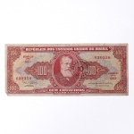 Numismática / Cédulas do Brasil. Cédula de 100 Cruzeiros, República dos Estados Unidos do Brasil, 2ª Estampa, Série 695A, número 030358. Anverso em tonalidades vermelha, vermelho-rosada, bege e verde-azulada, com efígie de D. Pedro II em medalhão central, ladeada por rosáceas com o valor facial 100; inscrições Tesouro Nacional, República dos Estados Unidos do Brasil e Cem Cruzeiros  Valor Legal. Apresenta carimbo circular de revalidação monetária do Banco Central, com a inscrição BANCO CENTRAL  10 CENTAVOS, aplicada em 1967 para conversão do valor original de 100 Cruzeiros em 10 centavos de Cruzeiro Novo. Reverso em tonalidade vermelho-rosada, com composição alegórica da Cultura Nacional, representada por figura feminina sentada junto a globo, livros e instrumentos, tendo paisagem ao fundo. Impressão pela Thomas De La Rue & Company Limited, Londres. Brasil, circa 1953-1959; revalidada em 1967.