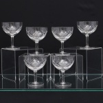 Conjunto de taças para champanhe em meio cristal, diáfano e incolor, de bojo hemisférico talhado com faixa geométrica composta por losangos facetados e cortes diagonais entrecruzados, fuste tubular apoiado sobre base circular. Composto de seis(06) unidades. Medidas. Altura 10,5 x Diâmetro: 8,5 cm.