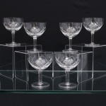Conjunto de taças para champanhe em meio cristal, diáfano e incolor, de bojo hemisférico talhado com faixa geométrica composta por losangos facetados e cortes diagonais entrecruzados, fuste tubular apoiado sobre base circular. Composto de seis(06) unidades. Medidas. Altura 10,5 x Diâmetro: 8,5 cm.