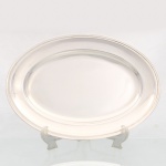 WOLFF. Elegante travessa confeccionada em metal espessurado à prata, formato oval, centro ligeiramente rebaixado, aba largam, borda percorrida por contorno relevado. Marca da manufatura no verso. Medidas: Comp.: x Larg.: cm.