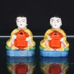 Par de queimadores de incenso em porcelana japonesa, período da Ocupação c.19451952. Modelados como figuras orientais sentadas, trajando vestes amarelas ornamentadas por motivos florais estilizados em vermelho, sobre bases retangulares esmaltadas em azul. Cada personagem sustenta recipiente de incenso em vermelho, provido de aberturas vazadas na cobertura para dispersão da fumaça. Policromia em amarelo, vermelho, verde, azul, preto e branco. Ao reverso, ampla abertura destinada à colocação do incenso. Bases com inscrição Made in Occupied Japan, correspondente à produção japonesa destinada à exportação durante o período de ocupação do Japão após a Segunda Guerra Mundial(19451952). Medidas: Alt.: 8,5 x Comp.: 6 x Larg.: 3cm.