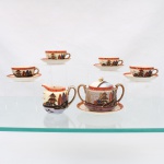 Serviço japonês para chá, período Showa, circa 19301950. Confeccionado em faiança esmaltada, composto por um(01) açucareiro, uma(01) leiteira, e quatro(04) xícaras com respectivos pires, ornamentados em esmaltes policromos e douração, apresentando composição paisagística com pagodes, formações rochosas, árvores, aves e cursos d'água; frisos em vermelho alaranjado com aplicações puntiformes em azul e branco. Bule de corpo globular, duas alças laterais e tampa abaulada com pomo esférico; leiteira de bojo arredondado, bico vertedor e asa lateral; xícaras com alças douradas e pires reproduzindo o mesmo repertório iconográfico. Marca em vermelho sob a base, composta por "H" inscrito em losango, caracteres japoneses e inscrição "Made in Japan". Medidas: Açucareiro: Alt.: 8,5 x Comp.: 12,5 x Larg.: 8 cm. Leiteira: Alt.: 7,5 x Comp.: 9 x Larg.: 6,5 cm; Xícara: Alt.: 3,5 x Comp.: 8 x Larg.: 6,5 cm. Pires: Diam.: 9,5 cm.